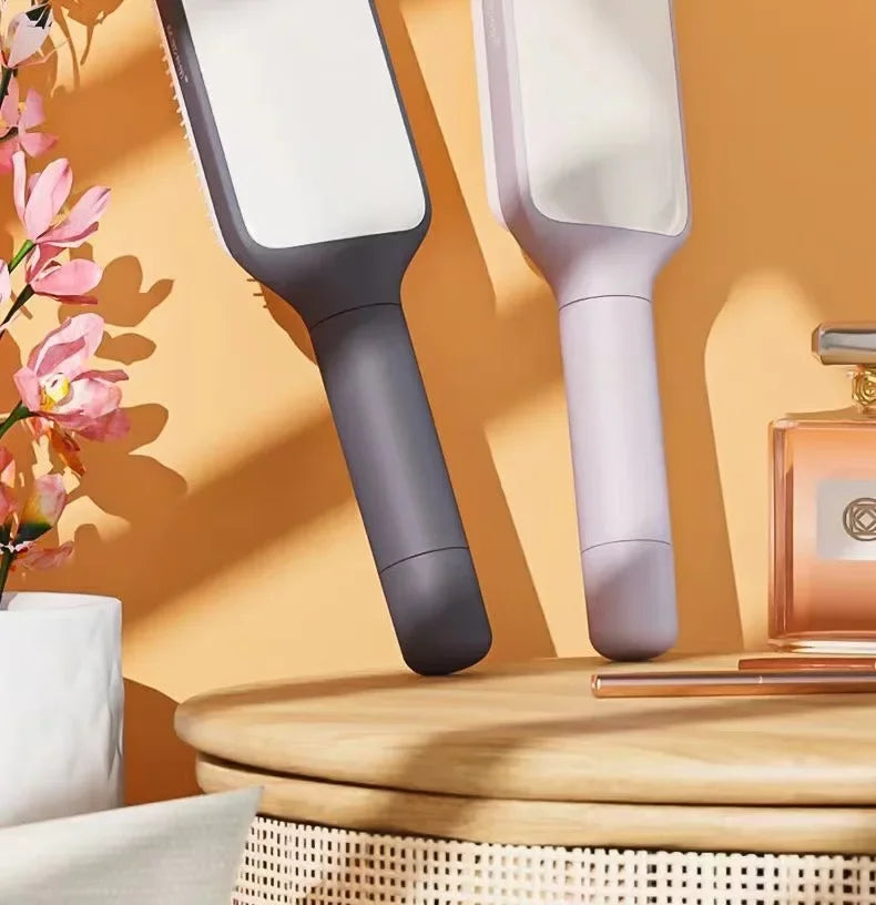 Two sleek pet grooming brushes in gray and lavender on wooden table with flowers and perfume